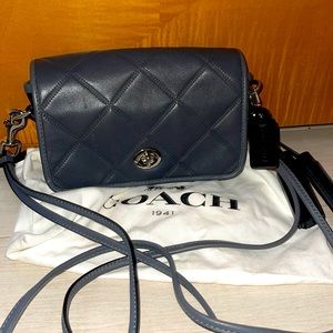 Dark gray quilted coach crossbody bag with adjustable straps with cover bag.